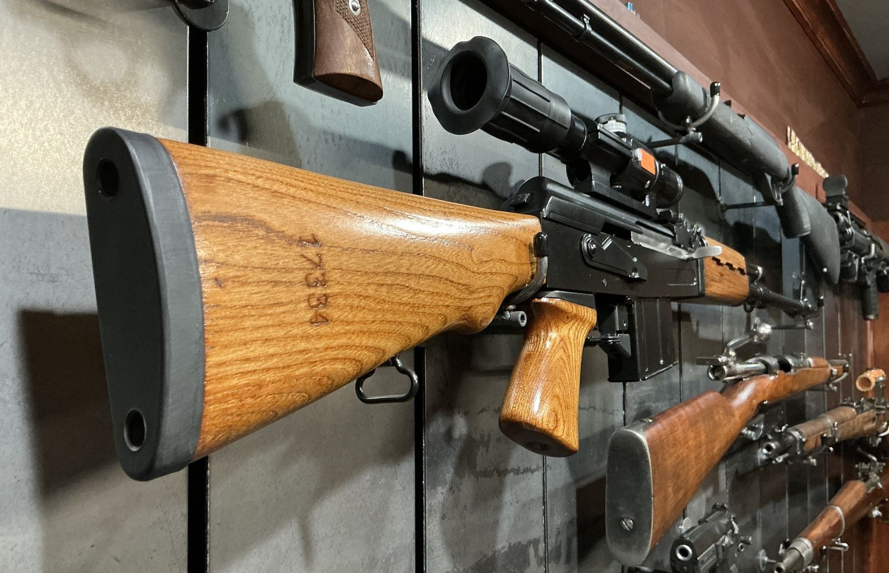 A wood-stocked rifle against the steel panel texture